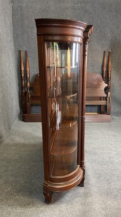 a wooden china cabinet with glass doors on the top and bottom, in front of a grey wall