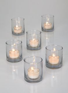 six clear glass tealight holders with candles in them