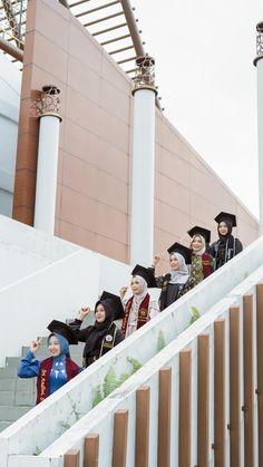 several people dressed in graduation gowns are standing on the stairs