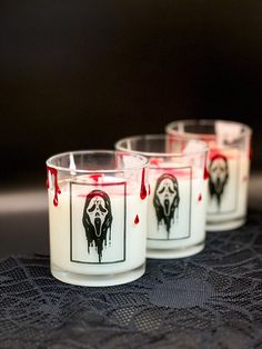 three candles with blood painted on them sitting on a lace covered tablecloth and black background