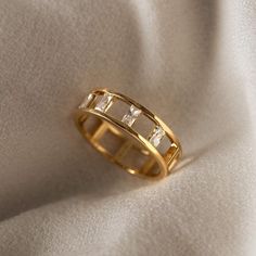 a gold ring with three baguettes sitting on top of a white cloth covered surface