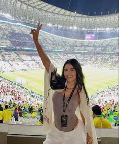 a woman standing in front of a large crowd at a soccer stadium with her arms up