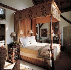 a bedroom with a four poster bed and orange drapes