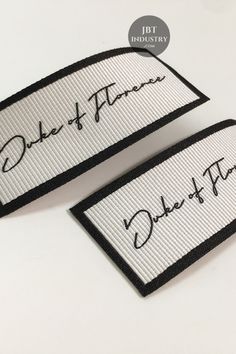 two white and black embroidered labels with the words duke of flowers on them in cursive writing