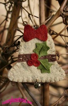 an ornament hanging from a tree with holly leaves and red berries on it