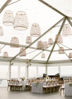 the inside of a tent with tables, chairs and chandeliers hanging from the ceiling