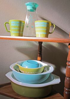 three bowls are stacked on top of each other in front of a shelf with glass pitchers