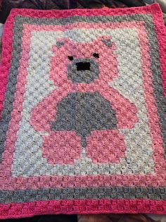 a crocheted blanket with a pink teddy bear on the front and gray back