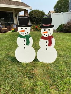 two snowmen are standing in the grass