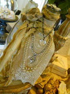 an old fashion necklace is displayed on a table next to other antique items and glass vases