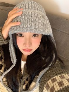 a woman wearing a gray knitted hat with long black hair is posing for the camera