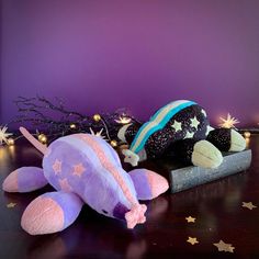 a purple stuffed animal laying on top of a wooden table next to a christmas tree