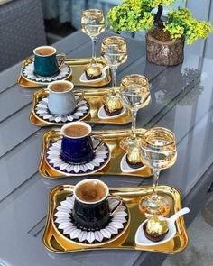 there are coffee cups and saucers on the trays with gold rimmed dishes