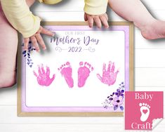 a baby's first mother's day card with pink handprints and flowers