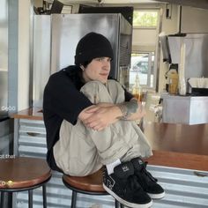 a man sitting on top of a stool next to a counter