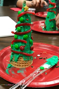 two red plates with green christmas trees on them, one is half eaten and the other half has been decorated