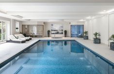 an indoor swimming pool with blue water and plants in the middle, surrounded by white walls