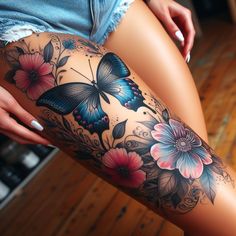 a woman's thigh with flowers and butterflies on her leg, while she is showing off her tattoo