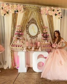 a woman in a pink dress standing next to a table with cakes and cupcakes