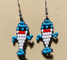 two blue and white beads are attached to some kind of earring that is shaped like a cartoon character