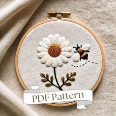 there is a embroidery pattern with a flower and a bee on the front, as well as a banner that says pdf pattern