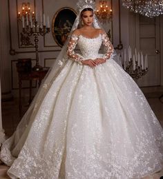 a woman in a white wedding dress standing next to a chandelier