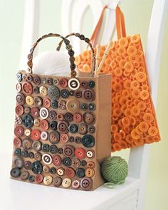 two bags with buttons on them are sitting next to yarn and crochet balls