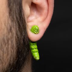 a close up of a person's ear with a green pea pod attached to it