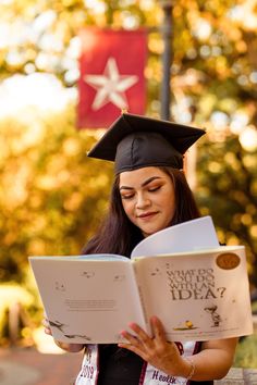 a woman wearing a graduation cap and gown reading a book