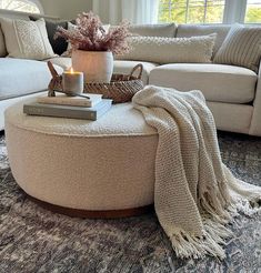 a living room filled with furniture and a large round coffee table covered in a blanket