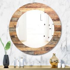 a round mirror sitting on top of a wooden table next to a vase and potted plant