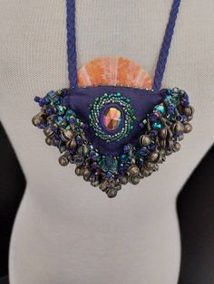 This fun necklace is handmade and hand beaded purple deerskin, with a beautiful whole pecten scallop shell and vintage metal dance bells and irradescent glass beads hanging. It makes a wonderful tinkling sound when worn and rattled. It measures 4"x4" with a 19" adjustable beaded leather strap. A one of a kind statment piece. Made with love💜 Unique One Of A Kind Purple Necklace, Handmade Purple Bohemian Necklaces, Handmade Purple Bohemian Beaded Necklaces, Handmade Bohemian Purple Beaded Necklaces, Purple Handmade Bohemian Necklaces, Bohemian Handmade Purple Beaded Necklaces, Handmade Amulet Beaded Necklaces For Rituals, Unique Purple Necklace, Purple Large Beads Jewelry For Festival