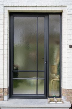 a cat is sitting on the window sill in front of a brick building with glass doors