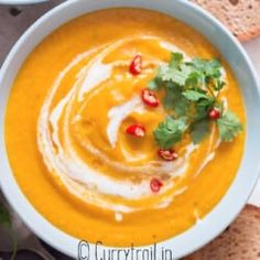 two bowls of soup with bread and garnishes on the side, ready to be eaten