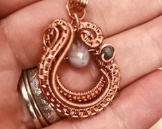 a person is holding a piece of jewelry in their hand and it looks like an intricate pendant