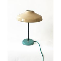 a lamp that is on top of a white surface with a green cord attached to it