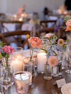 a wooden table topped with lots of vases filled with different types of flowers and candles