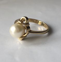 June Pearl is a vintage ring. Crafted in the mid-century in 14K yellow gold. The pearl is a natural, lustrous 6.8 millimeter round pearl. This simple ring will make a wonderful staple jewelry piece for someone who appreciates pearls or has a June birthday or anniversary month. The ring is very comfortable on the hand and tapers from 1mm to 2.18mm at the bottom of the shank. Currently a size 5.5 (Can be sized up or down upon request) Every Antique piece of jewelry we sell at Heirloom Pavé has bee Classic Gold Pearl Ring For Anniversary, Classic Yellow Gold Pearl Ring With Round Band, Classic Yellow Gold Pearl Promise Ring, Vintage Gold Hallmarked Pearl Ring, Antique 14k Gold Pearl Wedding Ring, Antique 14k Gold Pearl Ring For Anniversary, Antique Yellow Gold 14k Pearl Ring, Vintage Yellow Gold Pearl Ring For Formal Occasions, Classic 14k Stamped Pearl Ring For Wedding