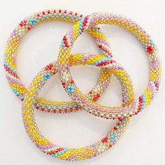 four bracelets with multicolored seed beads on white background, close up view