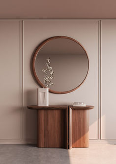 a round mirror sitting on top of a wooden table next to a vase filled with flowers