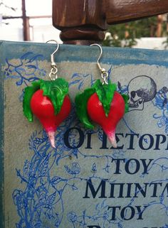 two red peppers with green leaves on them are hanging from the back of a sign