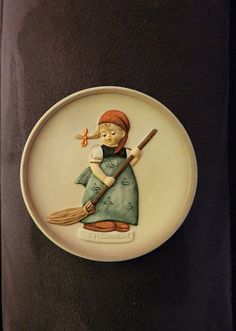 a ceramic plate with a woman holding a broom