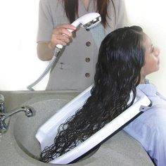 a woman is blow drying her hair in the bathroom sink while another person sits nearby