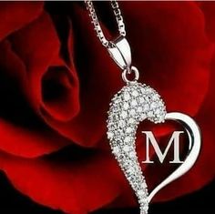 a heart shaped diamond pendant with the letter m on it and a rose in the background