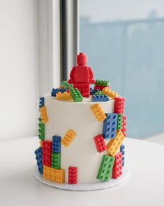 a white cake with legos on it sitting in front of a window