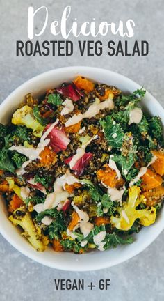 a white bowl filled with lots of vegetables and dressing on top of a gray surface