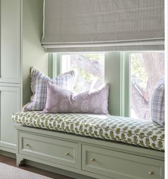 a window seat with pillows on it in front of a window sill and cabinets