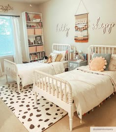 two twin beds in a bedroom with white walls and black and white patterned rugs