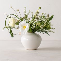 a white vase filled with flowers on top of a table