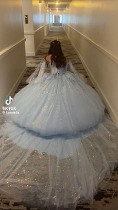 a woman in a blue ball gown walking down a hallway